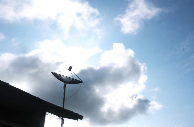 satellite antenna on rooftop with clouds in the background