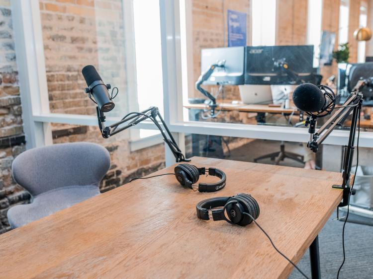 desk with headsets, microphones, screens in the background