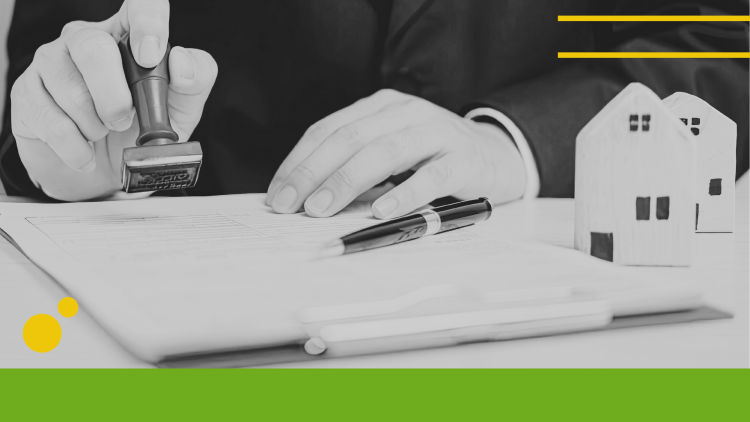 Person signing a document with models of houses next to them